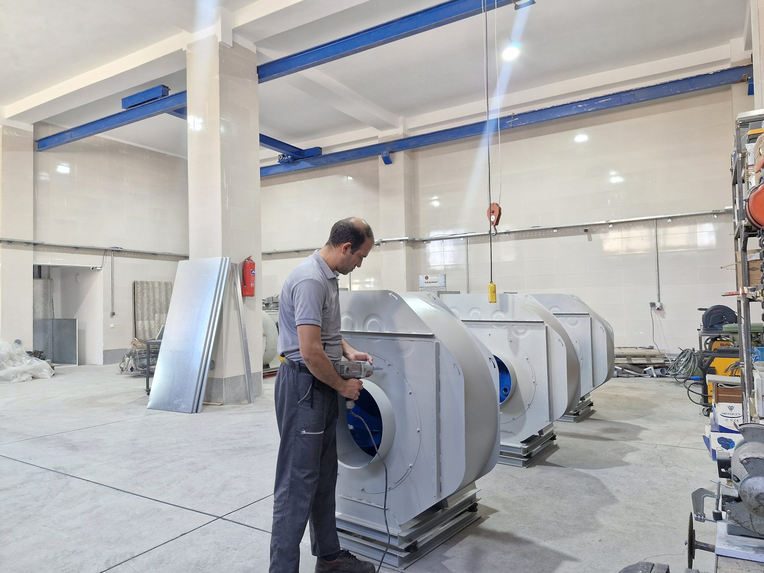 Operator using a power tool on a centrifugal fan casing in the workshop